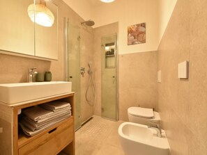 A modern bathroom with a glass-enclosed shower, a freestanding bathtub, and a toilet. - Charming Accommodation in Palau (Palau)