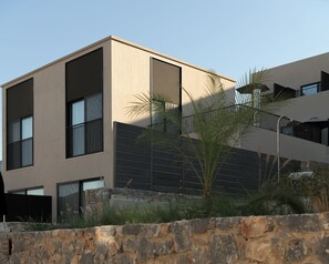 A modern building with a stone wall in the foreground, large windows, and a flat roof. - Neme Slow Living Retreat (Rethymno)