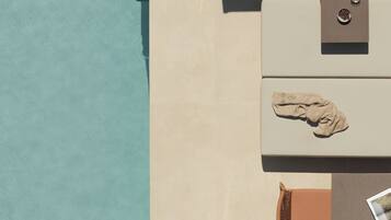 A top-down view of a room with a pool, a stone sculpture, and a towel on a chair.