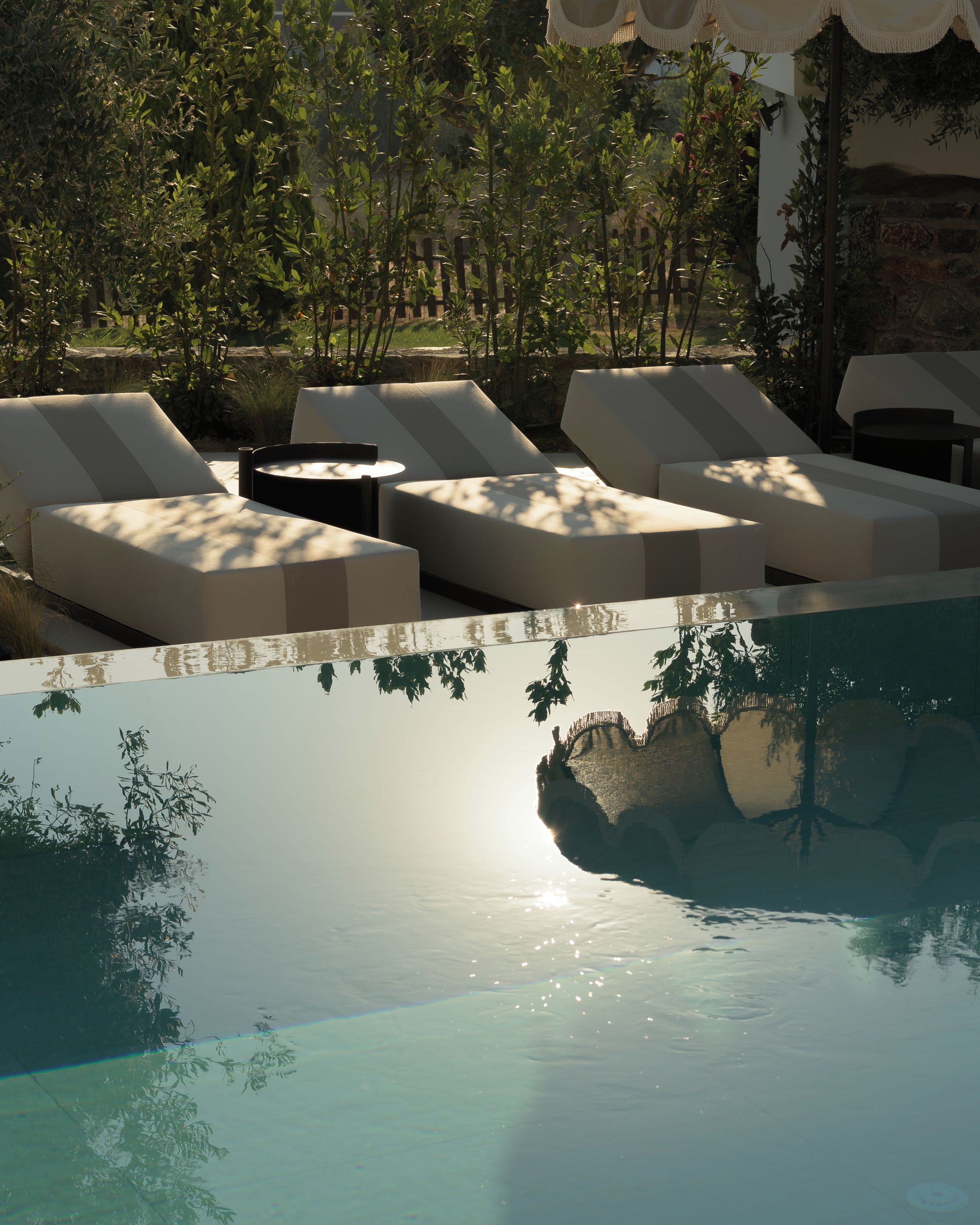 A poolside area with sun loungers and a stone wall.