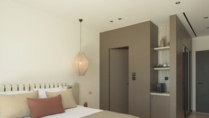 A modern bedroom with a large bed, a pendant light, a wardrobe, and a built-in coffee machine. - Neme Slow Living Retreat (Rethymno)