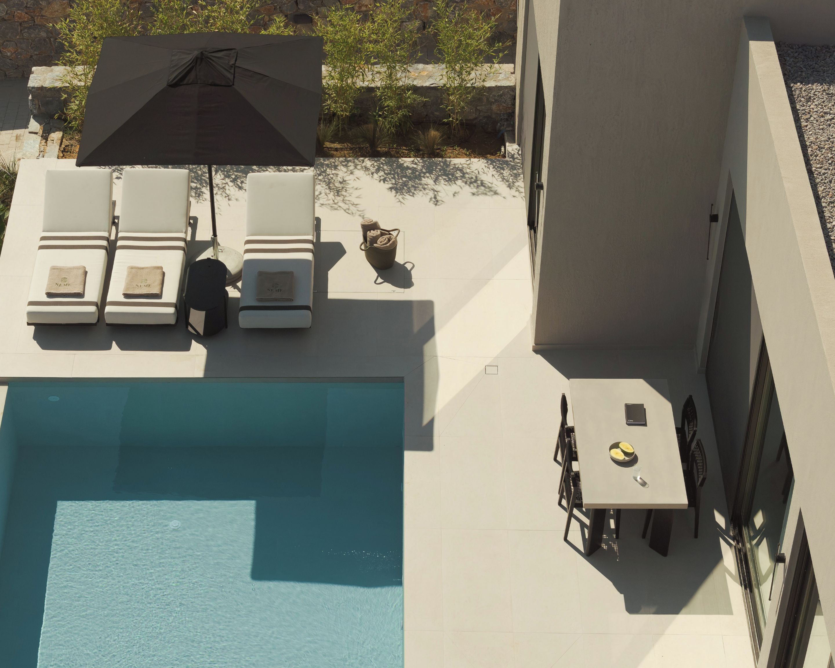 A rooftop pool area with lounge chairs and a table.