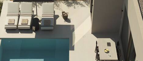 A rooftop pool area with lounge chairs and a table.