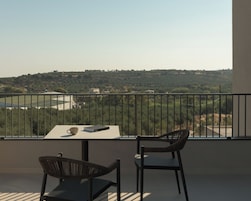 Un balcón con mesa y dos sillas, con vistas a un paisaje montañoso.