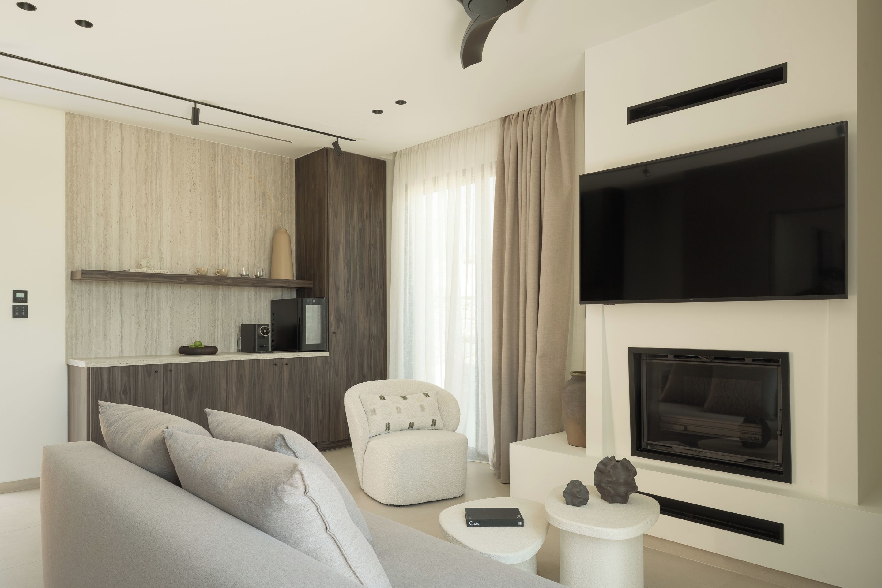 A modern living room with a sofa, armchair, fireplace, television, and a small side table.