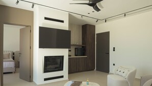 A modern living room with a fireplace, a sofa, a coffee table, and a TV. - Neme Slow Living Retreat (Rethymno)