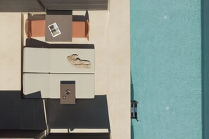 An aerial view of a rooftop terrace with a pool, a table, and lounge chairs. - Neme Slow Living Retreat (Rethymno)