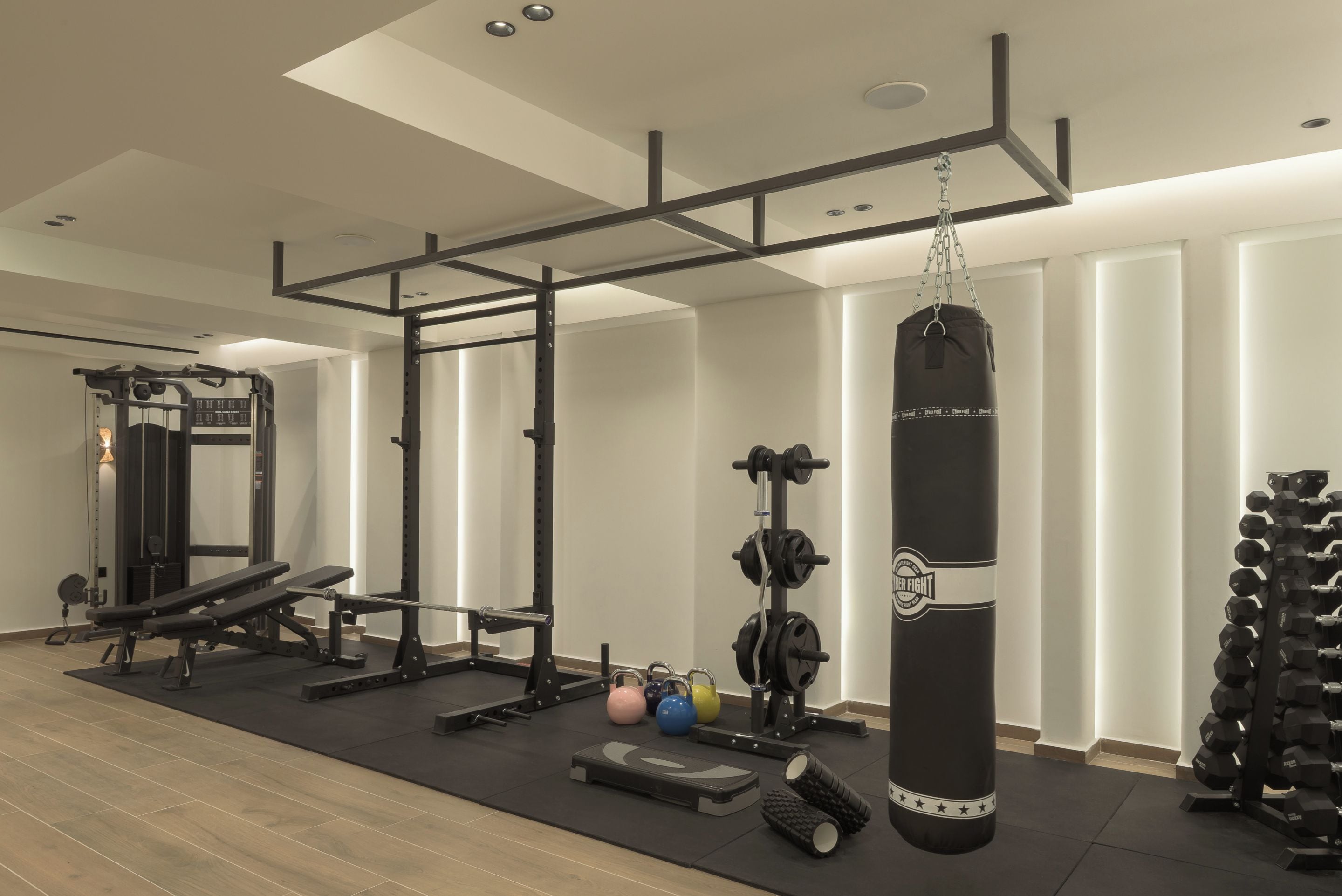 A gym with a pull-up bar, weight bench, kettlebells, and a punching bag.