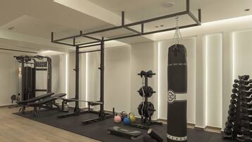 A gym with a pull-up bar, weight bench, kettlebells, and a punching bag.