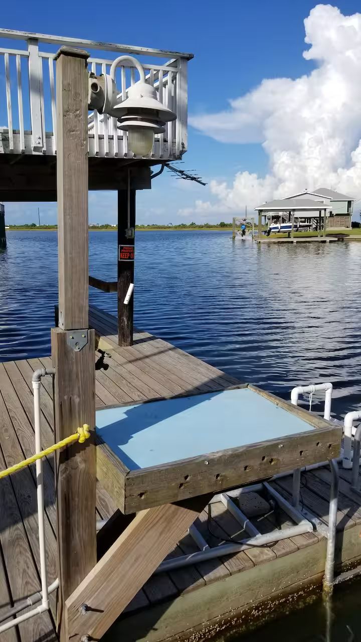 Un muelle de madera con barandilla metálica y una plataforma azul.