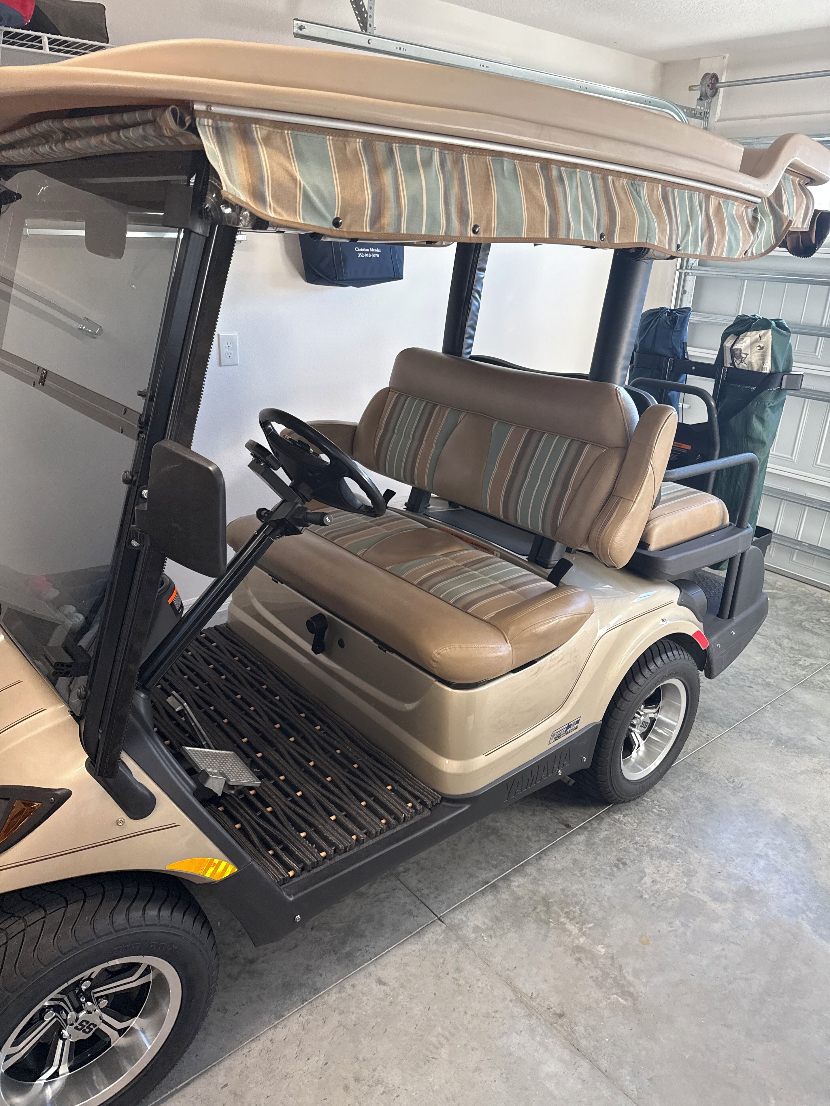 Une voiturette de golf avec un siège à rayures beiges et marron, un volant et le logo Yamaha.