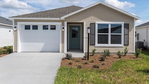 A single-story house with a garage, a front door, and a large window. - The Villages-Adorable Patio Villa with golf car located close to entertainment. (Sumterville)