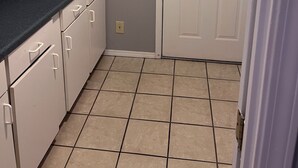 A kitchen with white cabinets, a dark countertop, and a white door with a window.