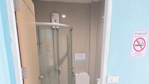 A bathroom with a glass-enclosed shower, a toilet, and a "No Smoking" sign. - Orca Guesthouse (Pattaya)