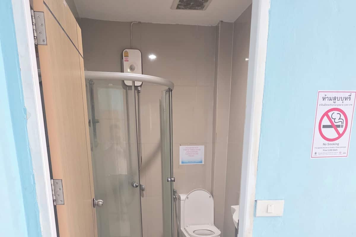 A bathroom with a glass-enclosed shower, a toilet, and a "No Smoking" sign.