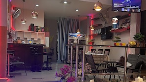 A restaurant with a modern interior, featuring tables set for dining, a television mounted on the wall, and ambient lighting. - Orca Guesthouse (Pattaya)