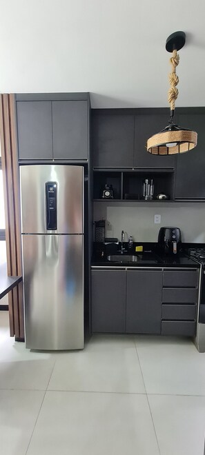 A modern kitchen with a stainless steel refrigerator, a built-in oven, and a coffee maker.