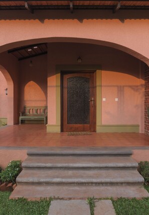 A building entrance with a wooden door, a bench, and steps leading up to it. - Flor De Lis - 4 BHK Villa w/Pool, wifi & parking behind Sakana in Anjuna (Vagator)