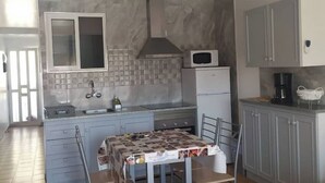 Eine kleine Küche mit gefliestem Rückspritzschutz, einer Mikrowelle, einem Spülbecken und einem Tisch mit Unterlage.