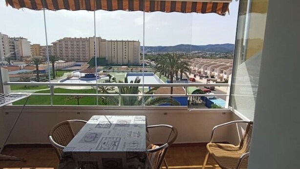 Ein Balkon mit Tisch und Stühlen, der auf einen Wohnbereich mit Gebäuden und Grünflächen blickt.