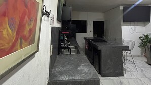 A modern kitchen with a marble countertop, a sink, and a dining area with chairs. - Mango house (Puerto Vallarta)