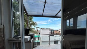 A room with a bed, a desk with a laptop, and a view of the outside. - Mango house (Puerto Vallarta)