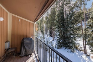 Un balcón de madera con vistas a un bosque nevado.