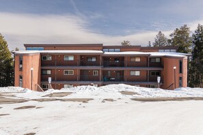A multi-story building with a wooden exterior, balconies, and a snow-covered ground. - Beaver Village Unit #0233 Renovated 2 bed vaulted ceilings, hardwood floor (Winter Park)