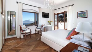 A bedroom with a large bed, a desk, a chair, a TV, and a view of the sea. - Seaview Villa Florinda with Private Pool near Sorrento Center Sleeps 8 Guests!!! (Sorrento)