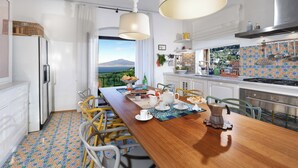A modern kitchen with a wooden dining table, white cabinets, and a view of a mountain. - Seaview Villa Florinda with Private Pool near Sorrento Center Sleeps 8 Guests!!! (Sorrento)