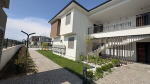 A modern residential building with a covered outdoor area, a staircase, and a pathway. - Nest Park Side | Evrenseki
 Modern & Lüks Daireler
 Havuzlu Site (Antalya)
