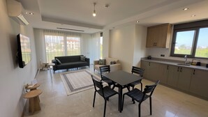 A modern living space with a dining area, kitchen, and seating area. - Nest Park Side | Evrenseki
 Modern & Lüks Daireler
 Havuzlu Site (Antalya)