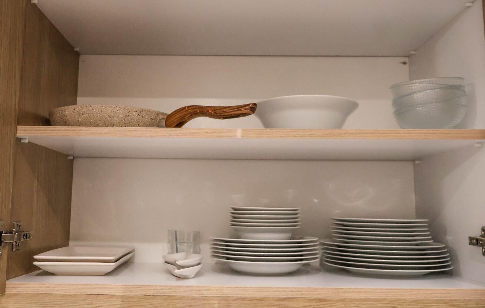 Un armario de cocina con estantes que guardan diferentes platos y una cuchara de madera.
