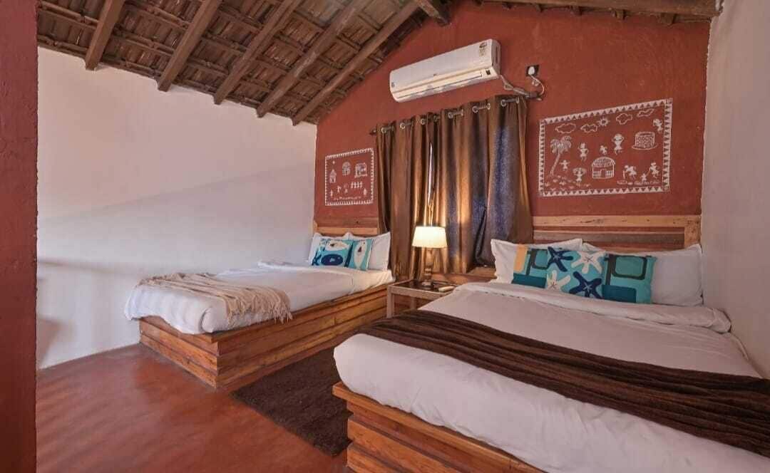 Ein Zimmer mit zwei Betten, Holz-Kopfteilen, einer wandmontierten Klimaanlage und einer Wanddekoration mit Muster.