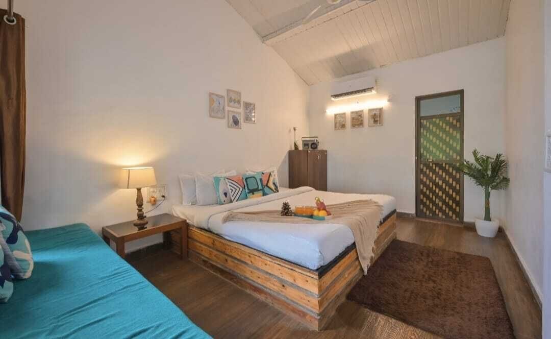 A bedroom with a bed, bedside table, lamp, and a potted plant.