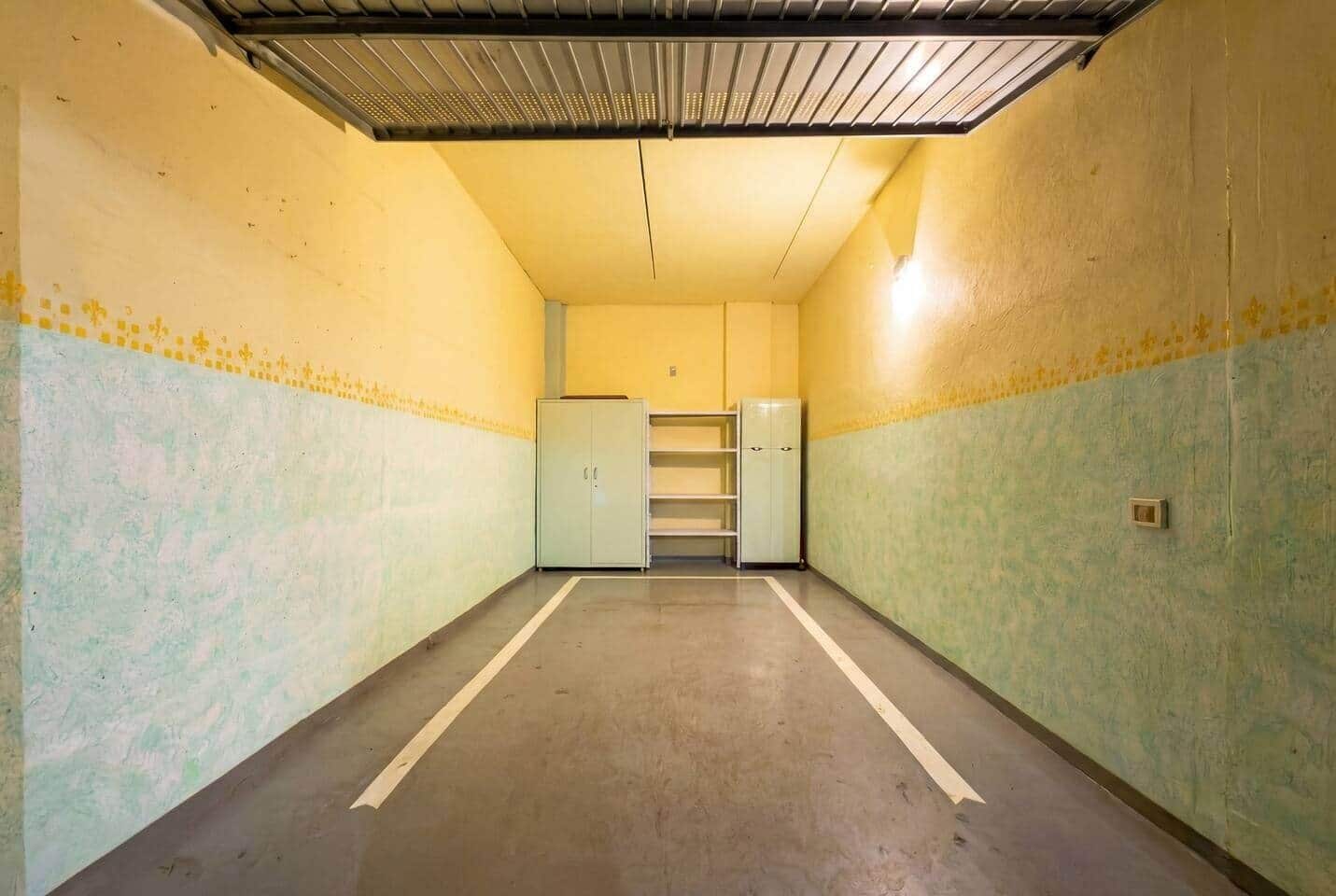 A narrow hallway with a ceiling vent, light fixtures, and a door at the end.