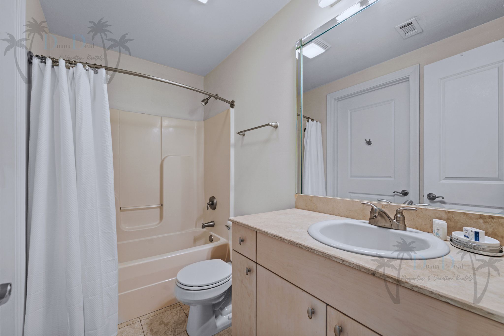 A bathroom with a bathtub, toilet, sink, and a large mirror.