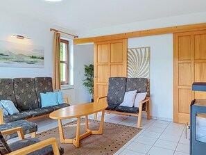 Ein Wohnzimmer mit einer Sofagarnitur, zwei Sesseln, einem Couchtisch und einer Holzkommode.
