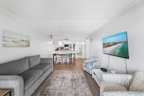 A modern living room with a grey sofa, a patterned armchair, and a flat-screen TV mounted on the wall. - Marigot Beach 811 (Ocean City)