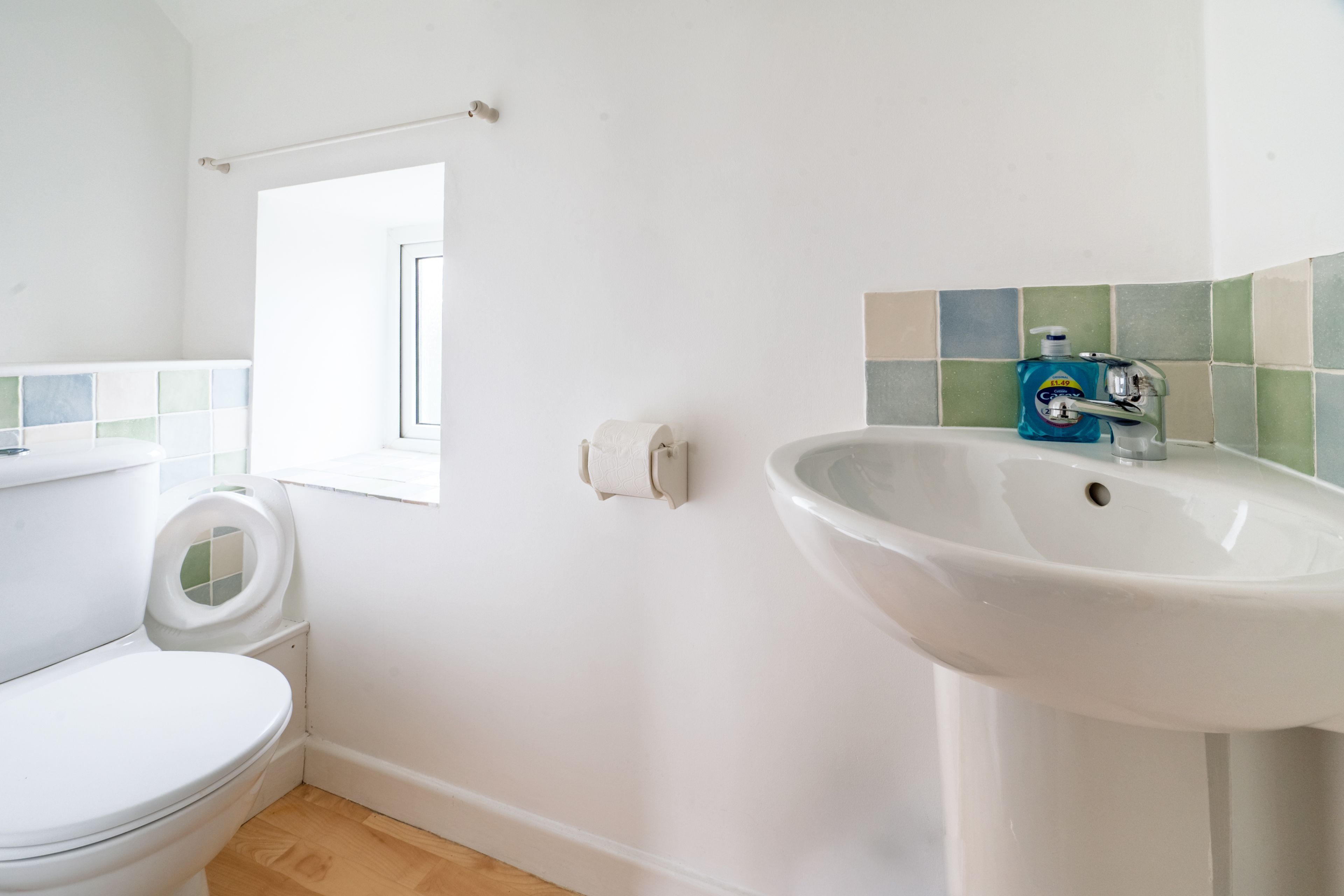 Une salle de bain avec des toilettes, un lavabo et une fenêtre.