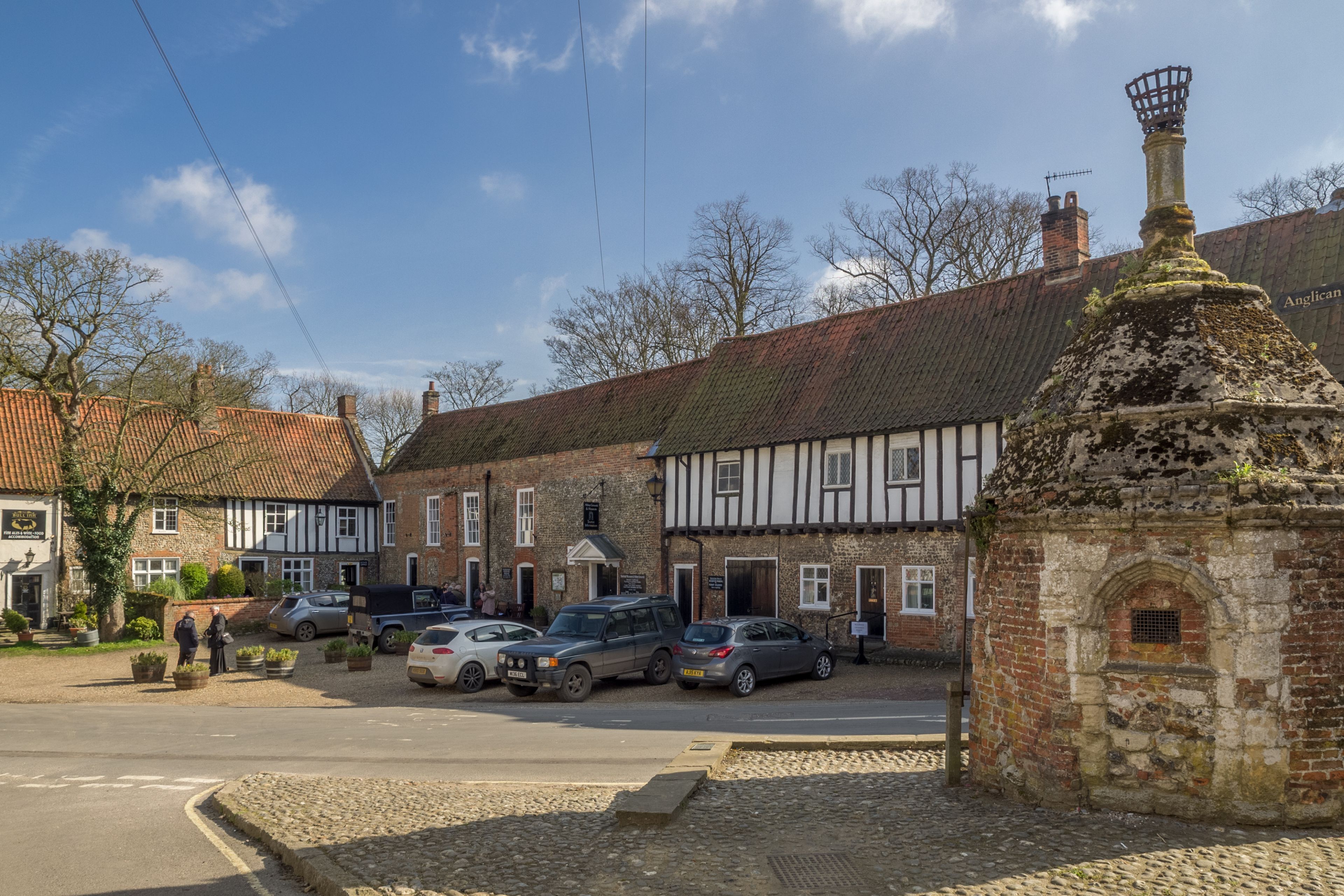 A traditional building with a Tudor-style facade, a cobblestone street, and parked cars.