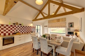 A spacious kitchen with wooden beams, a checkered backsplash, and a dining area with a table set for four. - Pheasant Cottage, Little Massingham, Norfolk (Little Massingham)