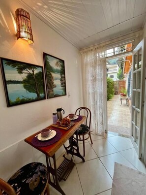Zona pranzo con tavolo apparecchiato per due persone, due quadri con paesaggi e una lampada a sospensione.