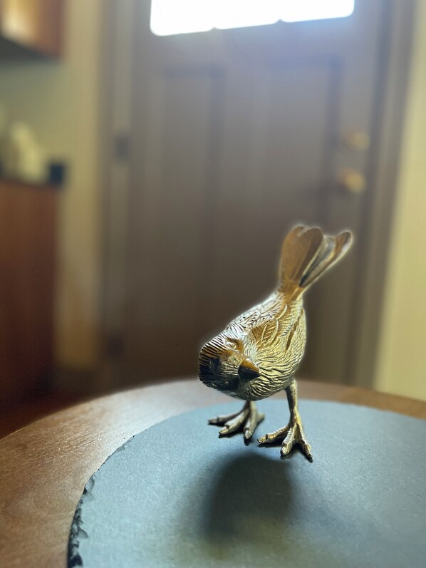 Una piccola statuina di un uccello su una superficie scura.