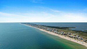 A coastal area with a long stretch of beach and a row of buildings along the shore. - Steele Away by Liquid Life (Gulf Shores)