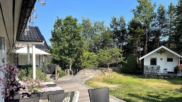 A patio area with outdoor furniture, a potted plant, and a small building in the background. - Large House With Pool and Close to the sea (Akersberga)