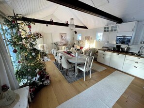 A spacious kitchen with white cabinets, a dining area with a white table and chairs, and a Christmas tree with ornaments. - Large House With Pool and Close to the sea (Akersberga)