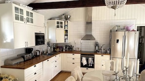 A kitchen with white cabinets, a wooden countertop, a built-in oven, and a stainless steel refrigerator. - Large House With Pool and Close to the sea (Akersberga)