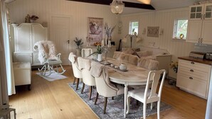 A dining area with a round table, white chairs, and a chandelier. - Large House With Pool and Close to the sea (Akersberga)
