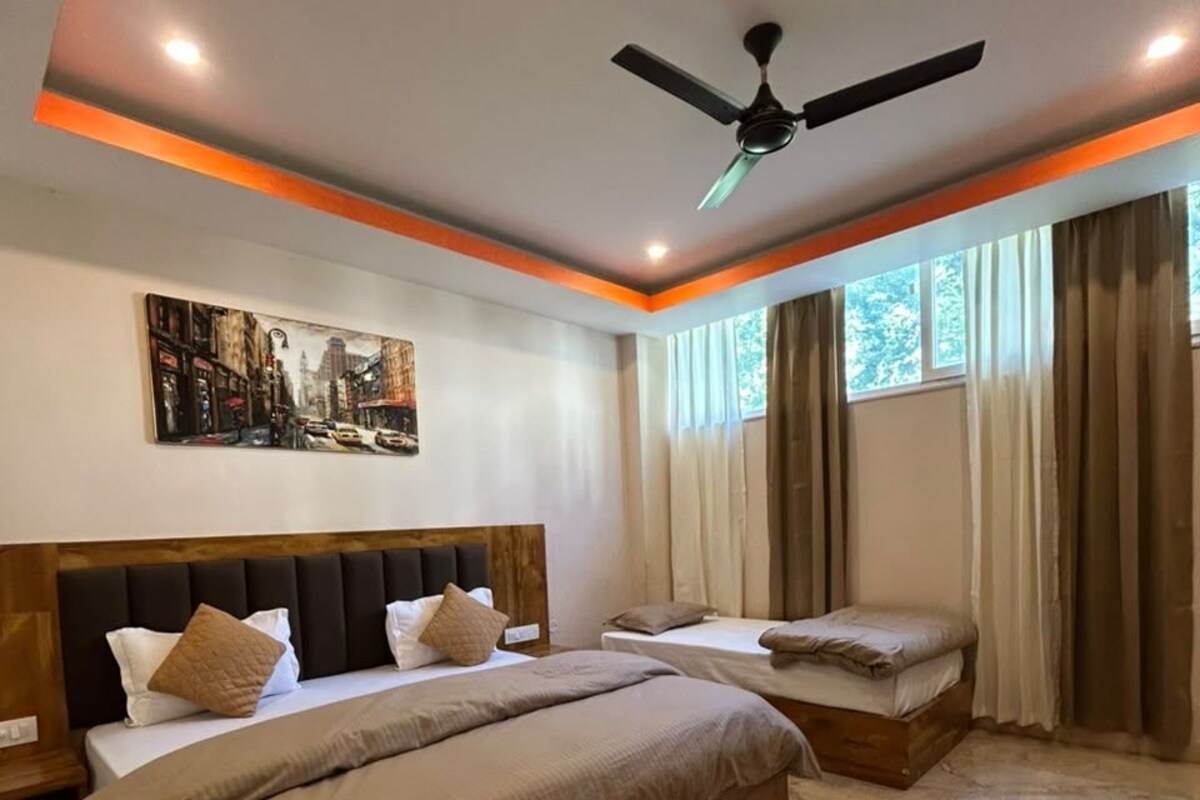 Quarto com duas camas, um ventilador de teto e uma pintura com vista para a cidade.